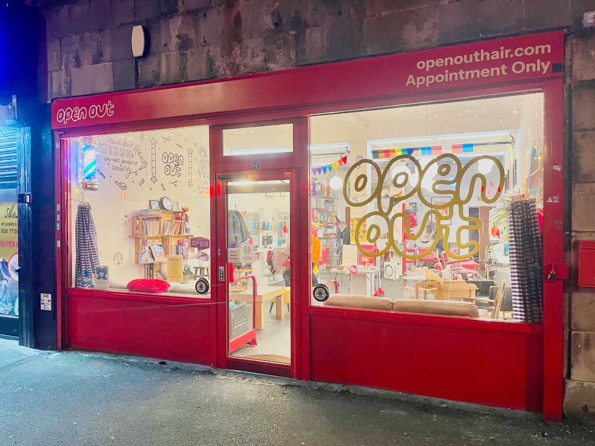 Open Out has a red shop front and a colourful interior including a hairdressing set up and comfy sofas and things to read.