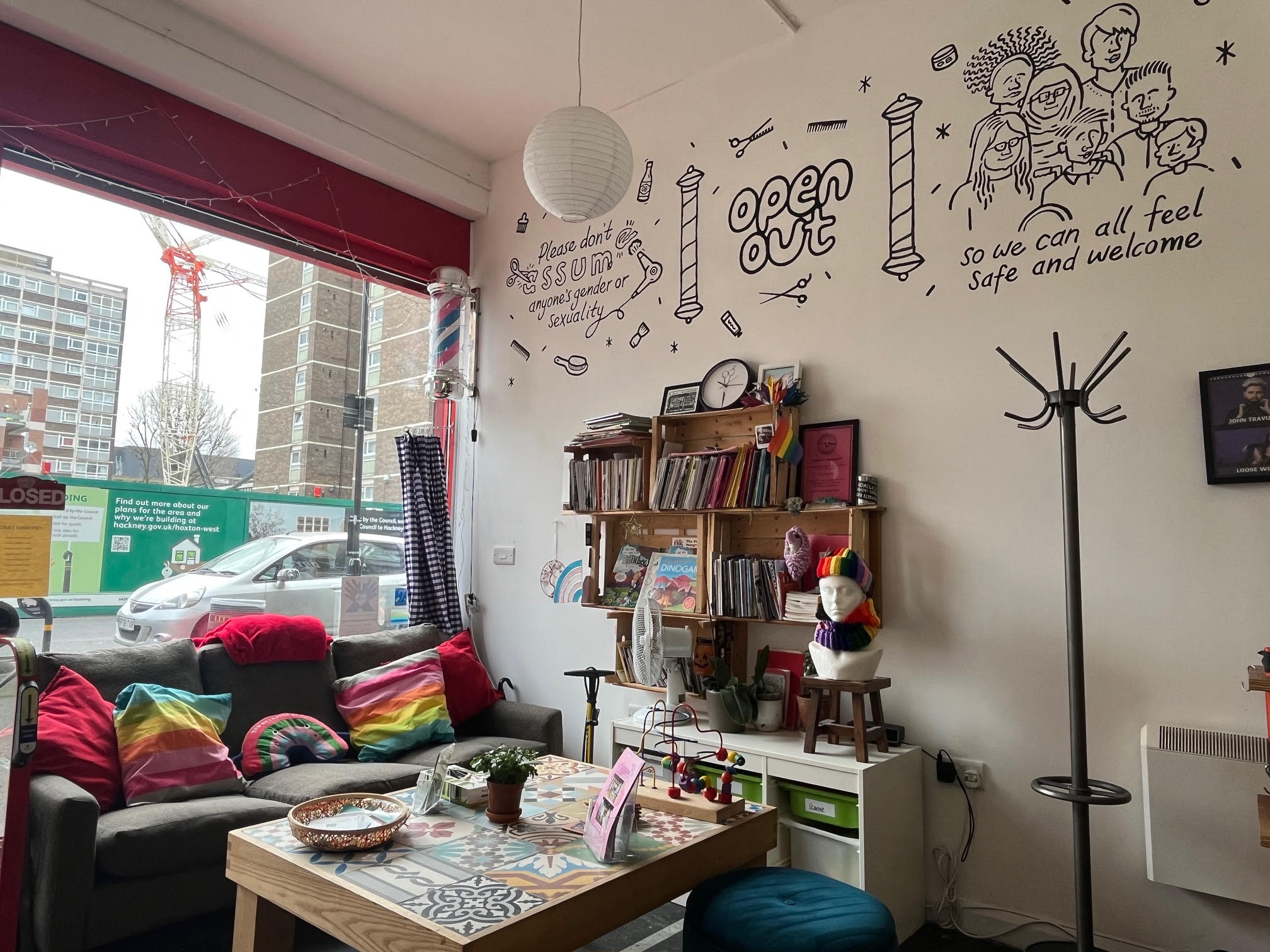 An interior view of Open Out with a sofa, table, reading material and a mural on the wall